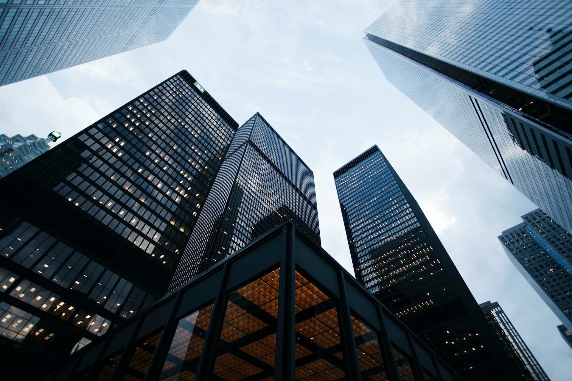 Aerial view of a modern downtown business district at golden hour with sleek glass office towers and warm light reflecting across the cityscape